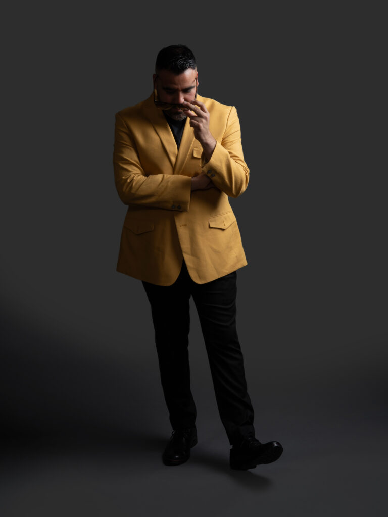 RETRATO DE MODELO CON LENTES Y SACO COLOR MOSTAZA Y PANTALON NEGRO ELEGANTE