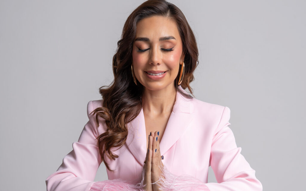 CONDUCTORA DE TELEVISION VESTIDO CON UN TRAJE EN COLOR ROSA EN FONDO BLANCO