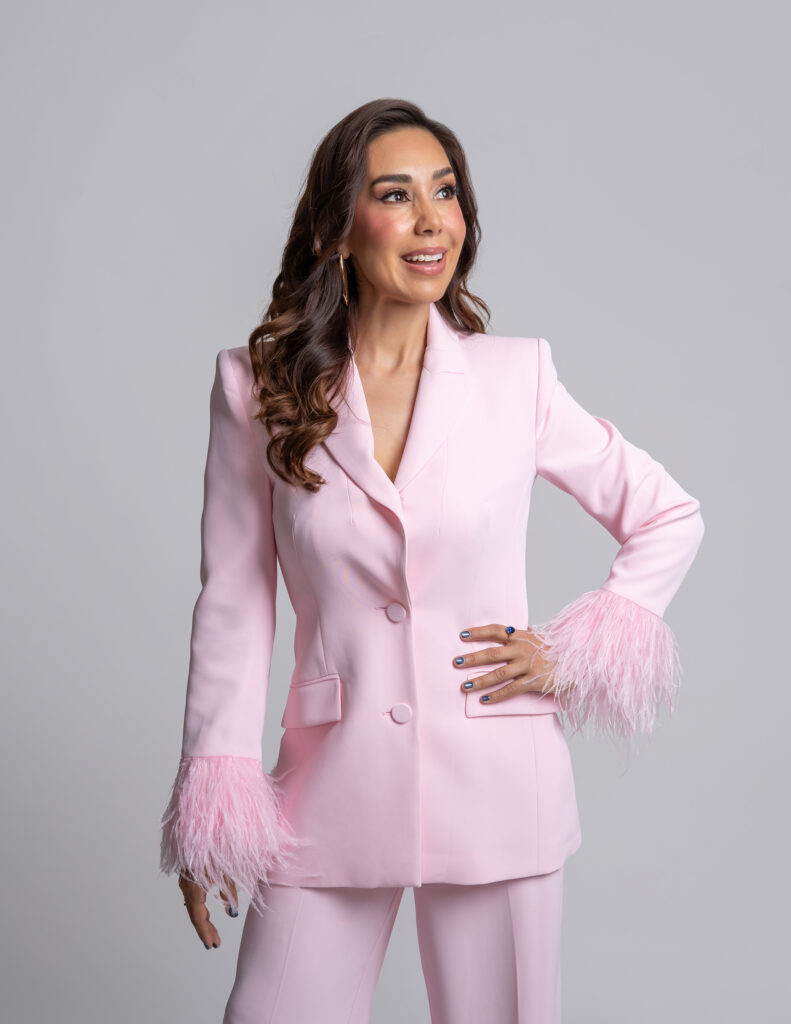 CONDUCTORA DE TELEVISION VESTIDO CON UN TRAJE EN COLOR ROSA EN FONDO BLANCO