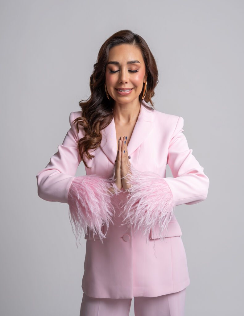 CONDUCTORA DE TELEVISION VESTIDO CON UN TRAJE EN COLOR ROSA EN FONDO BLANCO MEDITANDO