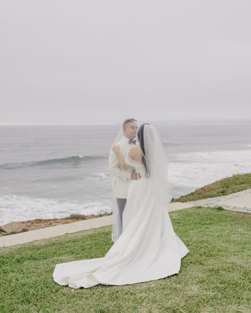 FOTOGRAFIA DE NOVIOS CUBIERTOS POR EL VELO FRENTE AL MAR EN VENTANA AL MAR VENUE