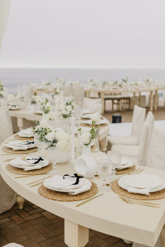 FOTOGRAFIA DEL MONTAJE EN DONDE SE VE LA DECORACION DE LA MESA, FLORES, COPAS, PLATO Y BAJO PLATO JUNTO CON EL MENU IMPRESO, CUCHARA, TENEDOR Y CUBIERTO
