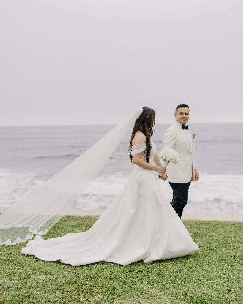 FOTOGRAFIA DE NOVIOS TOMADOS DE LA MANO CAMINANDO FRENTE AL MAR EN VENTANA AL MAR VENUE